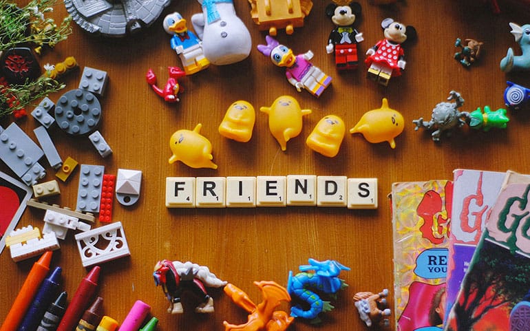 Photo of scrabble letter spelled out in Friends surrounded by toys, legos and magazine.