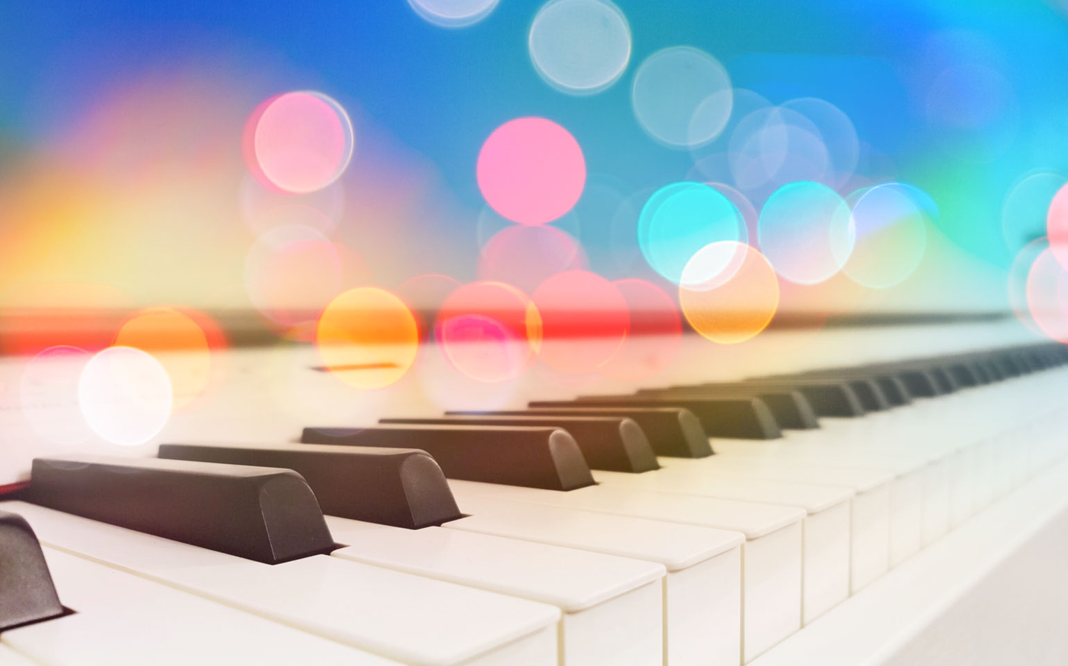 The ivory keys of a piano are shown with glowing lens flare spots above them.