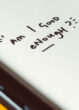 A note in a notebook reads "am I good enough?"